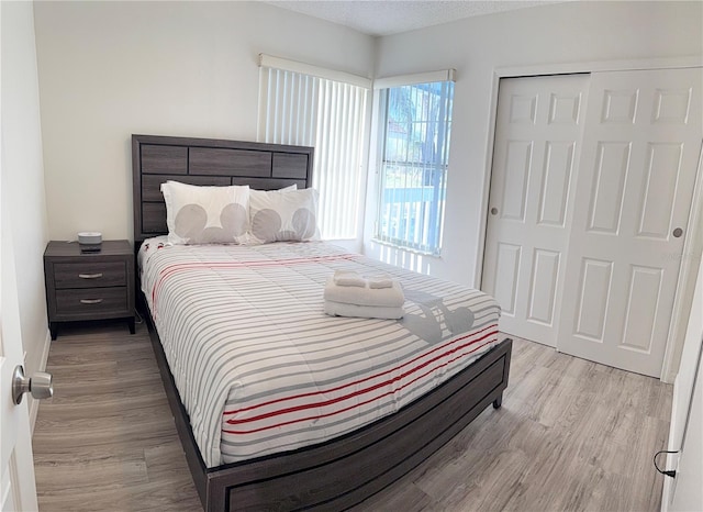 bedroom with a textured ceiling, light hardwood / wood-style flooring, and a closet