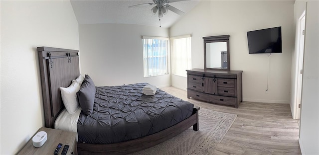 bedroom featuring a textured ceiling, light hardwood / wood-style flooring, vaulted ceiling, and ceiling fan