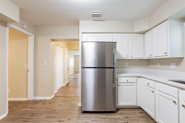 kitchen with white cabinets, stainless steel fridge, and light hardwood / wood-style floors