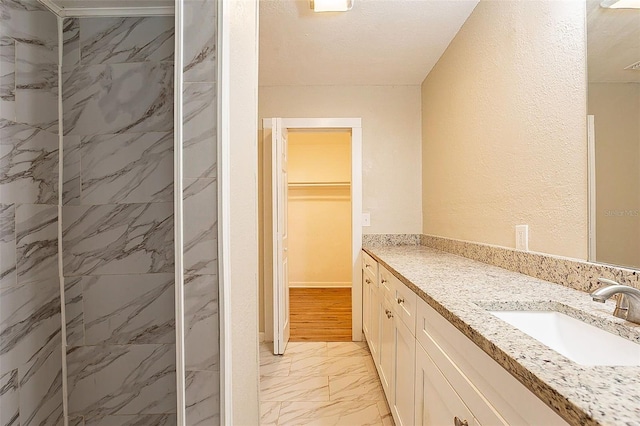 bathroom featuring hardwood / wood-style floors, vanity, and tiled shower