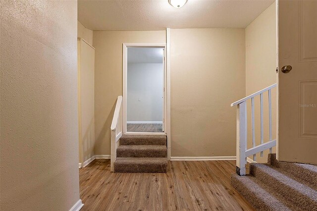 stairs with hardwood / wood-style floors and a textured ceiling