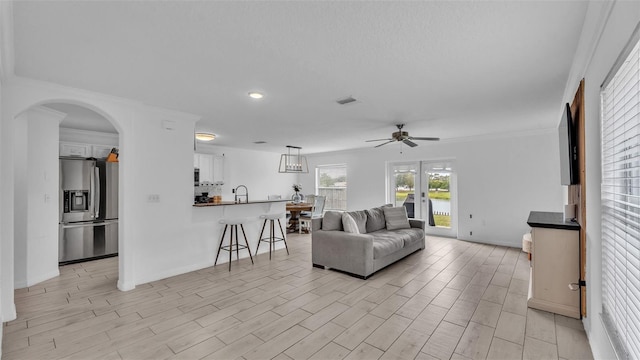 living room featuring ceiling fan, light hardwood / wood-style floors, ornamental molding, and sink