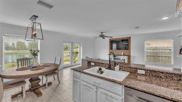 kitchen with sink, decorative light fixtures, dark stone countertops, dishwasher, and white cabinetry