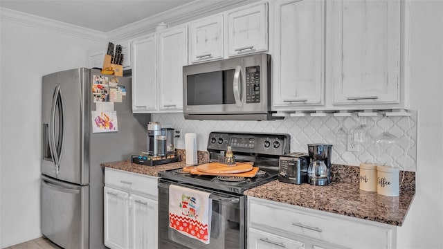 kitchen with tasteful backsplash, ornamental molding, stainless steel appliances, dark stone countertops, and white cabinetry