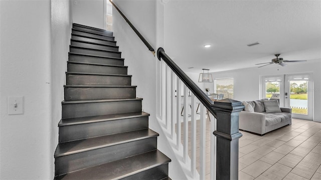 stairs with ceiling fan and french doors