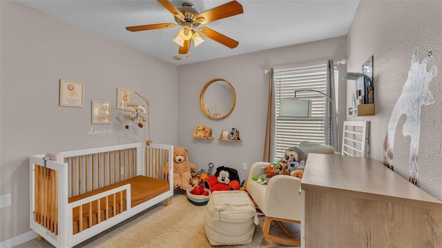 bedroom with ceiling fan and a nursery area