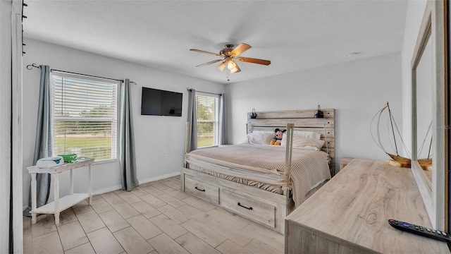 bedroom featuring a textured ceiling, light wood-type flooring, multiple windows, and ceiling fan