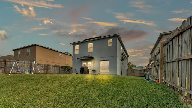 back house at dusk featuring a lawn