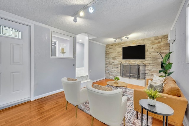 living room with a fireplace, wood-type flooring, a textured ceiling, and track lighting