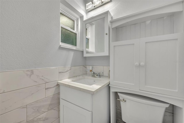 bathroom featuring vanity, tile walls, and toilet