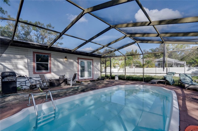 view of pool with glass enclosure, area for grilling, and a patio area