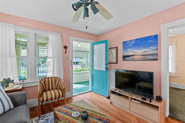 living room featuring ceiling fan, a healthy amount of sunlight, a textured ceiling, and hardwood / wood-style flooring