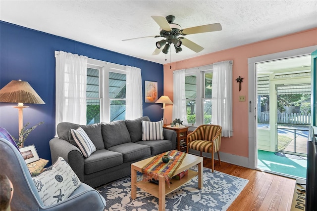 living room with hardwood / wood-style flooring, ceiling fan, and a textured ceiling