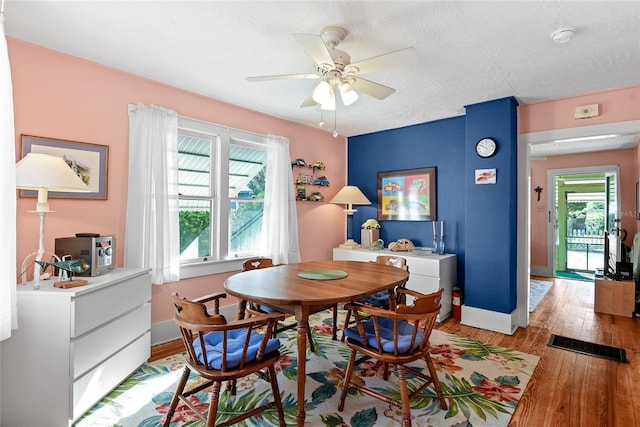 dining space featuring ceiling fan, light wood-type flooring, and a textured ceiling