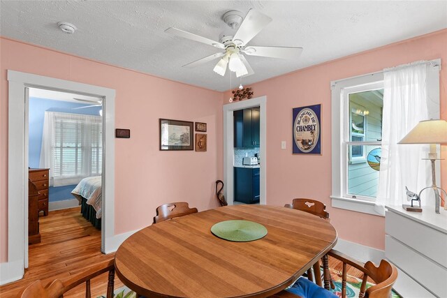 dining room featuring light wood-type flooring, a textured ceiling, and ceiling fan