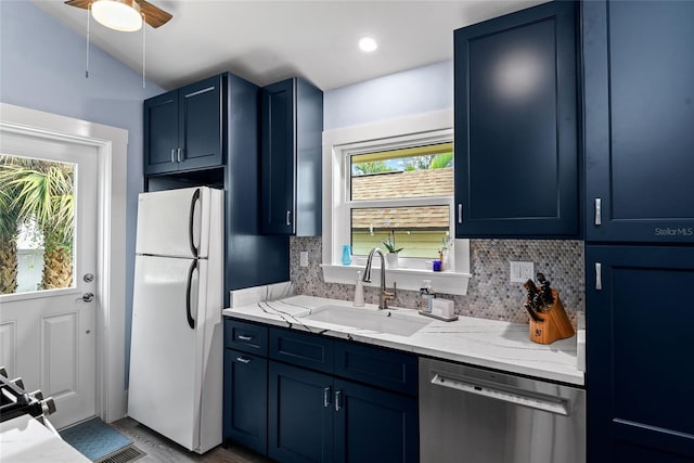 kitchen with light stone countertops, white fridge, stainless steel dishwasher, and blue cabinets