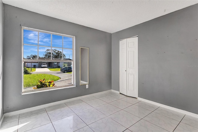 spare room featuring light tile patterned floors and a textured ceiling