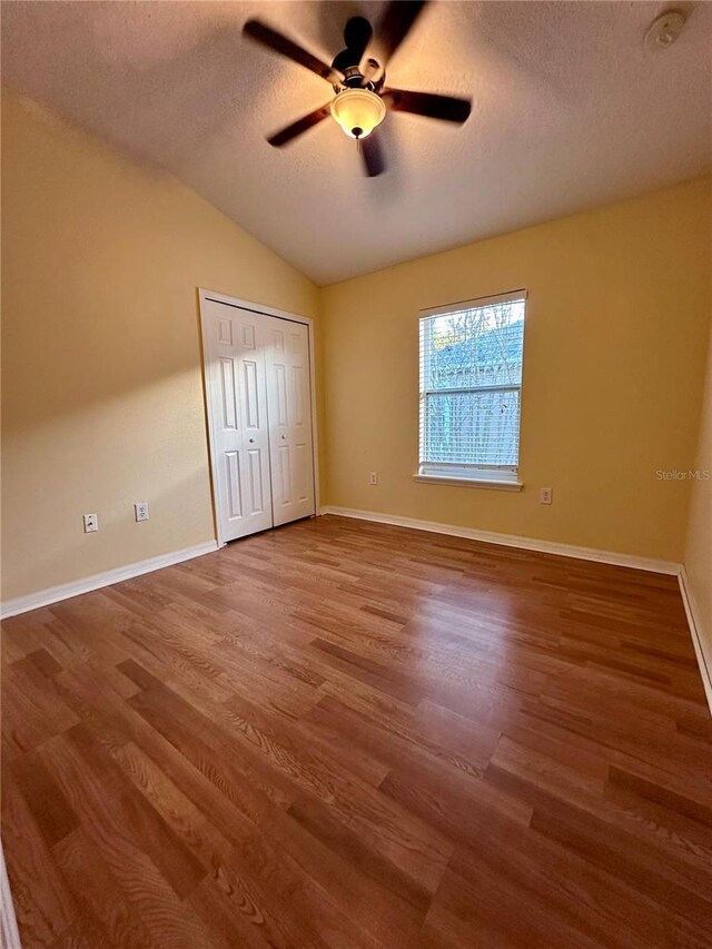 6430 S Goldenrod Rd Unit 15B, Orlando, FL 32822 - unfurnished bedroom featuring a textured ceiling, wood finished floors, a closet, vaulted ceiling, and baseboards