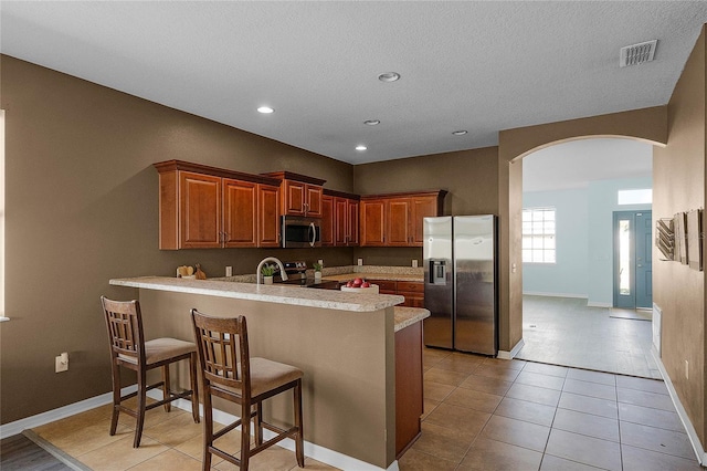 kitchen featuring appliances with stainless steel finishes, a kitchen breakfast bar, kitchen peninsula, and light tile patterned floors