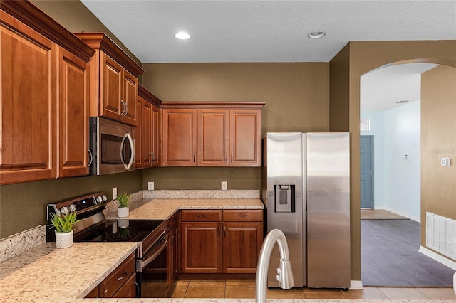 kitchen featuring light stone counters, appliances with stainless steel finishes, and light tile patterned floors