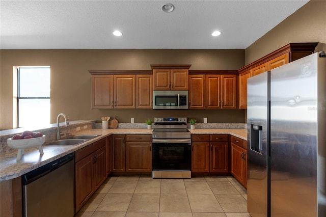 kitchen with appliances with stainless steel finishes, sink, light tile patterned floors, and kitchen peninsula