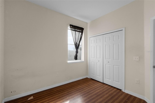 unfurnished bedroom featuring dark wood-type flooring and a closet