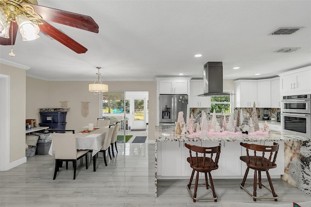 kitchen featuring kitchen peninsula, appliances with stainless steel finishes, decorative backsplash, extractor fan, and white cabinetry