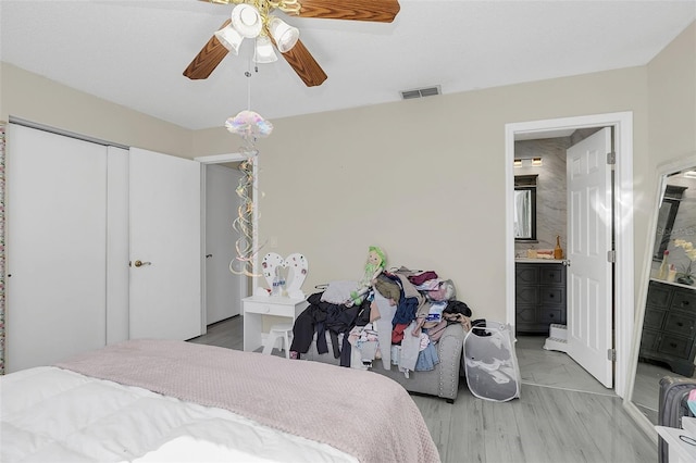 bedroom with ensuite bath, ceiling fan, a closet, and light hardwood / wood-style floors