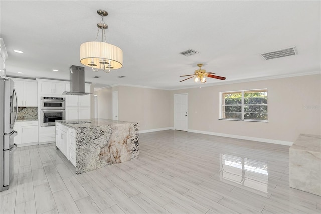 kitchen featuring pendant lighting, island exhaust hood, light stone counters, white cabinets, and a kitchen island