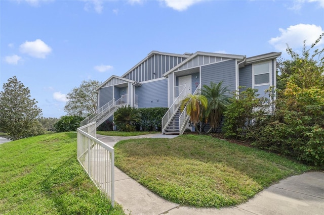 view of front of property featuring a front lawn, stairway, and board and batten siding