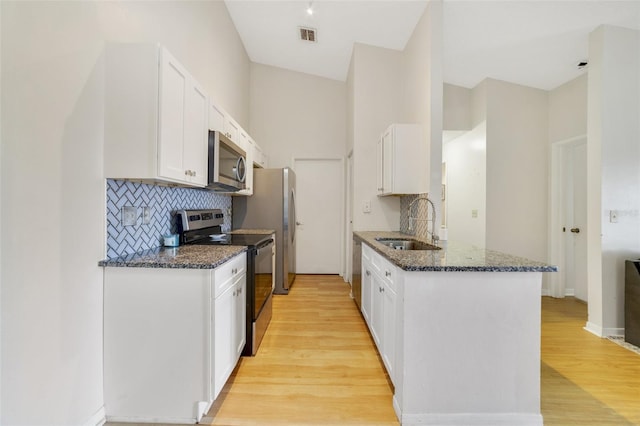 kitchen featuring appliances with stainless steel finishes, sink, white cabinets, and dark stone counters