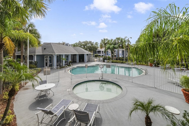 community pool featuring a patio, a community hot tub, and fence