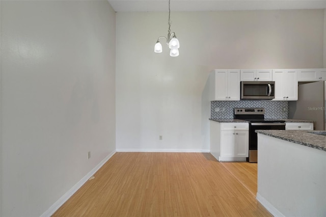 kitchen with a notable chandelier, tasteful backsplash, stainless steel appliances, light wood-style floors, and white cabinets