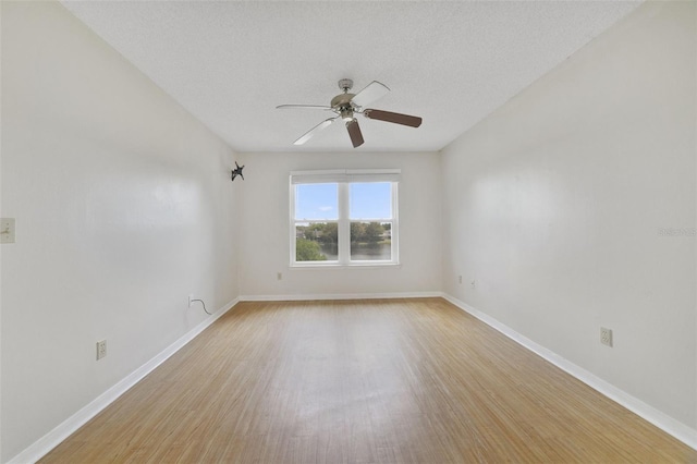 empty room featuring a textured ceiling, a ceiling fan, light wood-type flooring, and baseboards