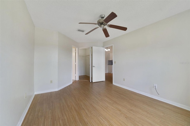 empty room with visible vents, baseboards, light wood-style flooring, a textured ceiling, and a ceiling fan