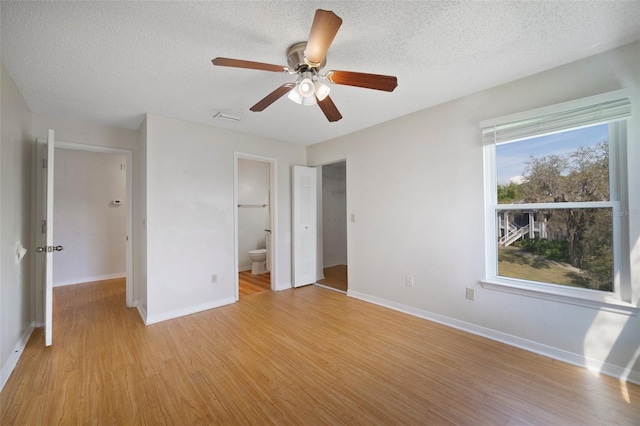 unfurnished bedroom featuring a textured ceiling, light wood-type flooring, and baseboards