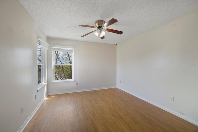 unfurnished room with a ceiling fan, light wood-style floors, baseboards, and a textured ceiling