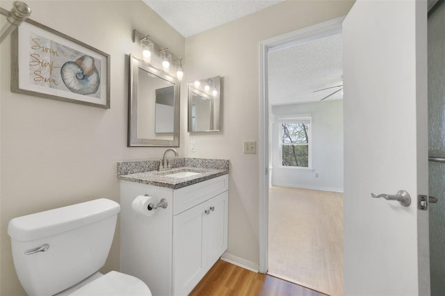 bathroom with vanity, toilet, wood finished floors, and a textured ceiling