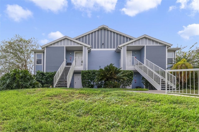 view of front of home featuring stairs, a front yard, and board and batten siding