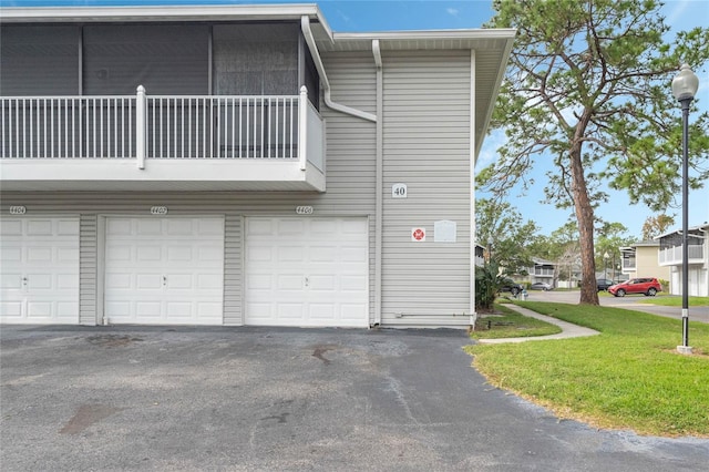 view of home's exterior featuring a balcony, a garage, and a lawn