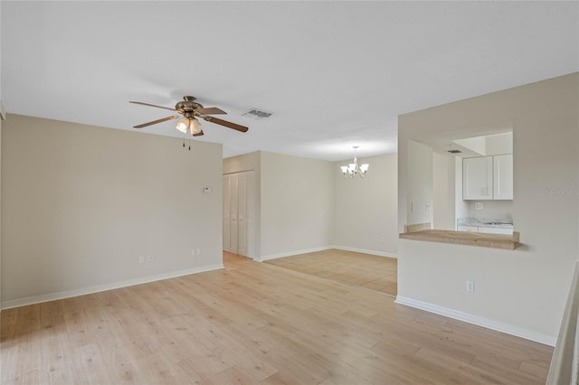 unfurnished living room with ceiling fan with notable chandelier and light hardwood / wood-style flooring