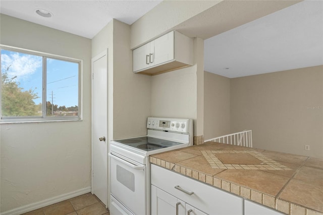 kitchen featuring white cabinets, tile countertops, white electric stove, and light tile patterned flooring