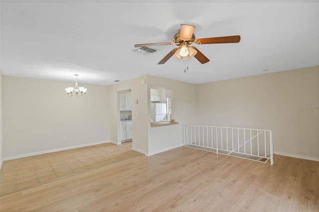 unfurnished living room with ceiling fan with notable chandelier and light wood-type flooring