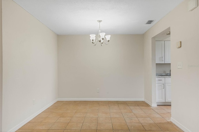 tiled empty room featuring a textured ceiling and a chandelier