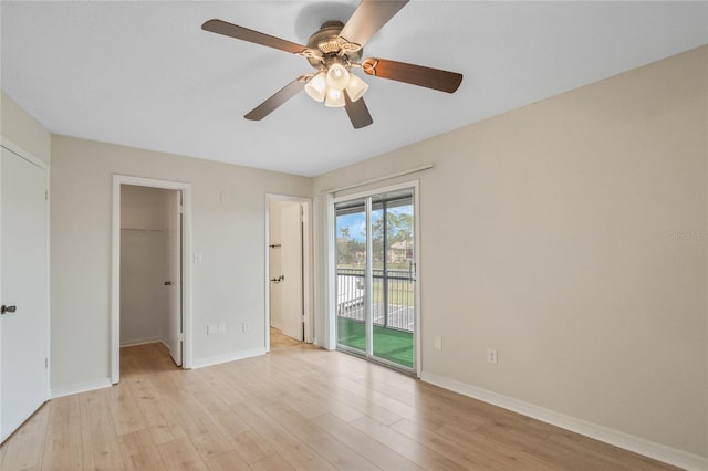 unfurnished bedroom with access to exterior, ceiling fan, a walk in closet, a closet, and light wood-type flooring