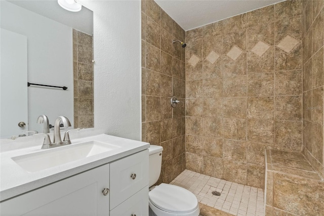 bathroom with tiled shower, vanity, and toilet