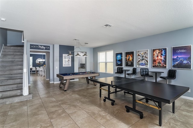 game room with a textured ceiling and an inviting chandelier