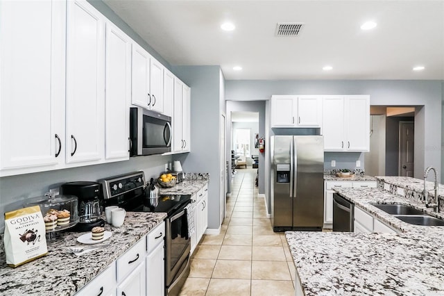 kitchen with light stone counters, stainless steel appliances, white cabinetry, and sink