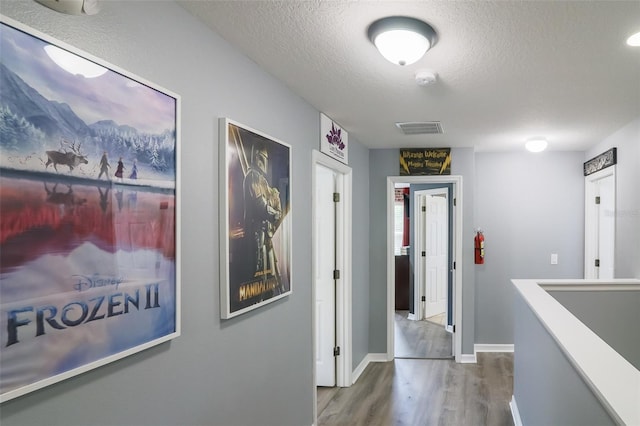 hall with wood-type flooring and a textured ceiling