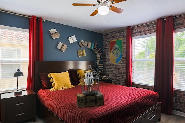 bedroom featuring hardwood / wood-style floors, ceiling fan, and brick wall